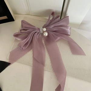 Détail d'un élégant nœud à cheveux en satin rose poudré avec perles blanches décoratives