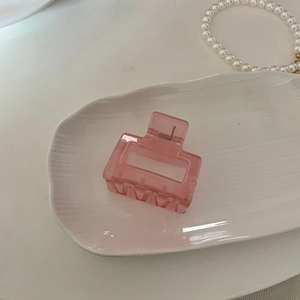 Détail d'une pince à cheveux en acrylique rose translucide avec ressort sur plateau