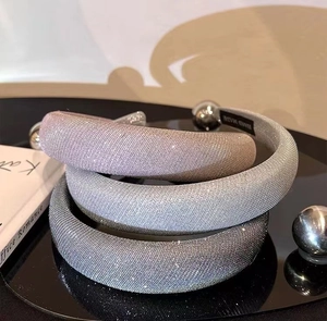 Detailaufnahme von drei Glitzer-Schwammhaarbändern in Rosa, Silber und Grau auf einem Tablett