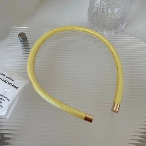 Détail d'un serre-tête en satin jaune vif avec d'élégants embouts en métal doré