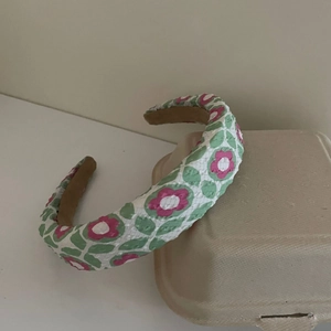 Detalle de diadema acolchada con estampado floral de flores rosas y hojas verdes