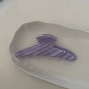 Pince à cheveux en acétate à texture marbrée violette sur un plateau en céramique