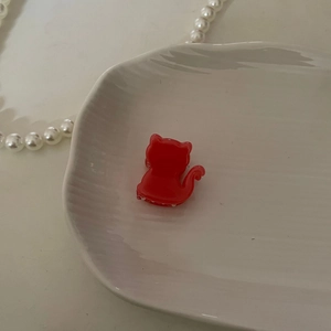 Pinza de pelo de gato rojo translúcido hecha de acetato en un plato blanco decorativo