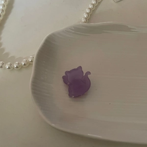 Lindo clip de pelo de gato en acetato lavanda sobre una bandeja de cerámica blanca