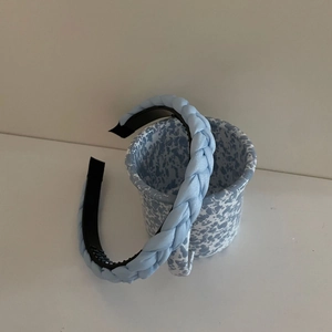 Detail of light blue braided headband showing non-slip teeth texture and glossy finish