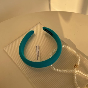 Detailed macro view of a turquoise sponge headband with handmade label on a tray