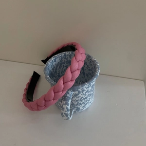 Detail view of a pink braided macaron headband resting on a ceramic blue pattern cup