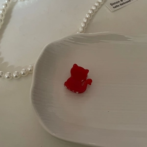 Detalle de una pinza para el cabello roja con forma de gato hecha de acetato fino