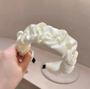 Detail view of cream pleated satin headband with elegant silk texture and soft padded ends