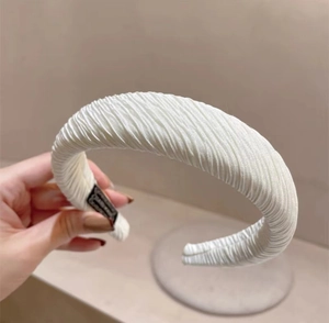 Macro detail of high-density pleated white fabric headband with delicate wavy texture