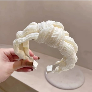 Detail of a creamy white pleated knotted headband showing the soft woven fabric texture