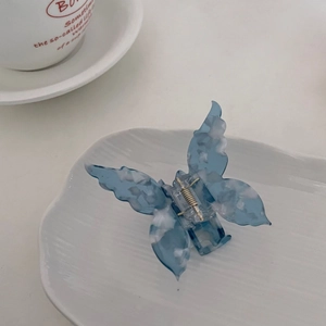 Détail d'une pince à cheveux papillon en acétate marbré bleu avec un ressort en métal doré