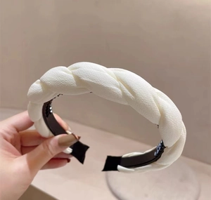 Detail of cream pleated woven headband featuring twist design and anti-slip teeth grip