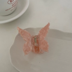Pince à cheveux papillon en acétate rose marbré avec ressort sur plateau blanc
