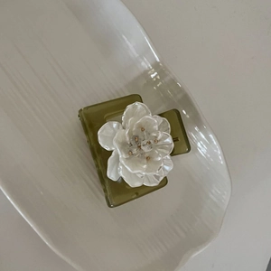 Olive green square hair claw clip with a large white 3D flower on a ceramic tray