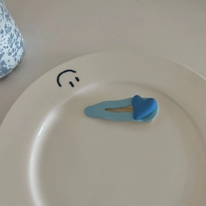 Schicke blaue Herz-Haarklammer mit mattem Finish auf minimalistischem Keramikteller