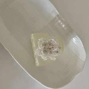 Macro detail of French flower hair claw clip with cream resin and golden pistil decoration