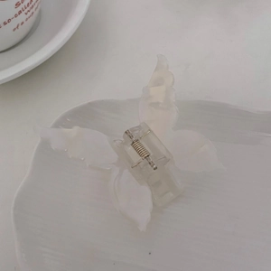 Détail d'une pince à cheveux papillon blanche avec ressort métallique sur assiette en céramique