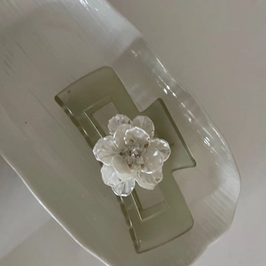 Detail of light green jelly hair claw clip with a white layered flower and gold bead