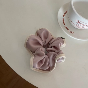 Detailed close-up of pink satin scrunchie with cream trim and elegant pleated texture