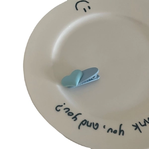 Minimalistische hellblaue Herz-Haarklammer mit mattem Finish auf einer weißen Porzellanplatte
