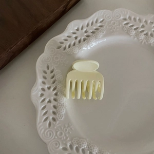 Petite pince à cheveux jaune clair mate pour queue de cheval sur une assiette décorative