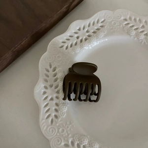 Gros plan d'une petite pince à cheveux mate marron foncé avec design à dents multiples