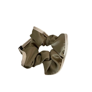 Olive green satin hair scrunchie with beige trim and soft pleats on white background