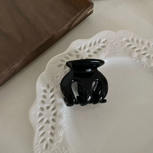 Détail d'une pince à cheveux noire brillante sur une élégante assiette en céramique