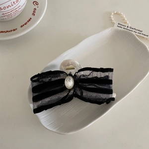 Elegant lace bow hair claw with crystal rhinestone decoration in a ceramic dish