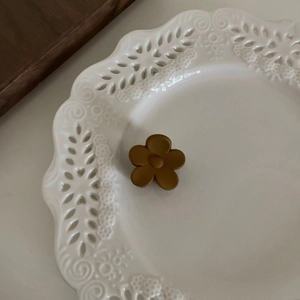 Pince à cheveux fleur marron mat minimaliste sur une assiette en céramique à dentelle
