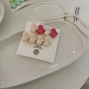 Detail of sweet heart-shaped macaron hair clips on a white ceramic display tray