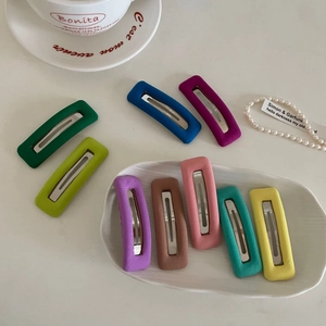 Close-up of nine colorful matte flocked snap hair clips arranged on a white tray