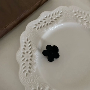 Gros plan sur la pince à cheveux fleur noire mate sur assiette en céramique dentelle