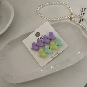 Colorful gradient heart hair clips in purple, green, and yellow on a ceramic tray