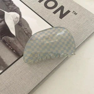Detail of blue and beige checkerboard acetate hair claw clip on a lifestyle magazine