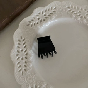 Gros plan d'une petite pince à cheveux noire mate sur une assiette décorative en céramique