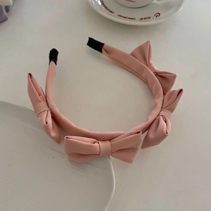 Close-up of pink satin headband featuring five 3D bows for French style hair styling