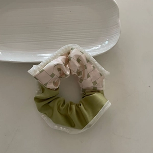 French style green and plaid patchwork scrunchie with lace trim on a white plate