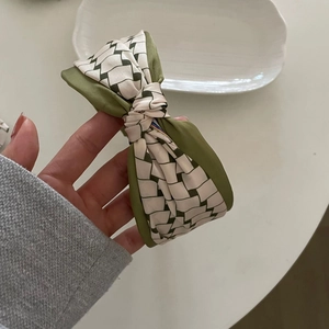 Detailed view of checkered green and beige bow headband with silk texture and retro style