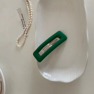Close-up of rectangular dark green sponge hair clip on a white ceramic tray decoration