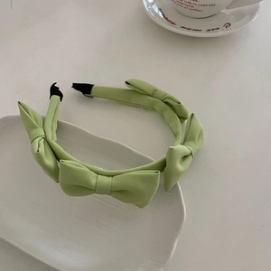 French style light green satin headband with multiple bows on a white ceramic tray