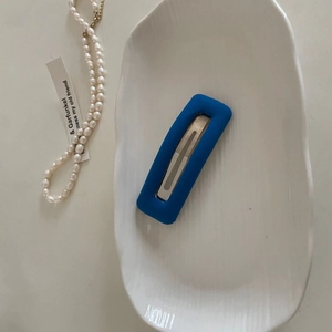 Close-up of a blue velvet sponge hair clip on a white ceramic tray with pearl beads