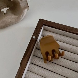 Pince à cheveux triangle marron caramel mat pour femme sur plateau en bois