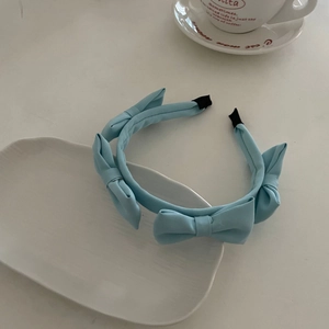 Detail view of a light blue satin bow headband on a ceramic tray with a coffee cup