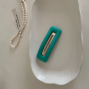 Detail view of a rectangular tiffany blue sponge hair clip on a white decorative tray