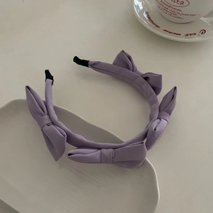 Detail of light purple satin headband with multiple bows on a minimalist table