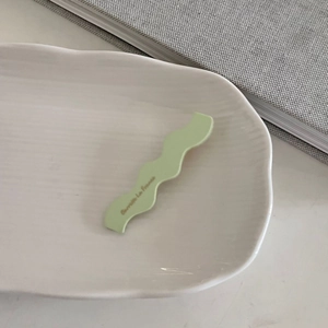 Primer plano de pinza ondulada verde claro con texto francés en bandeja de cerámica