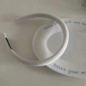 Dettaglio di un cerchietto imbottito bianco con tessuto a saia fine e piccola etichetta