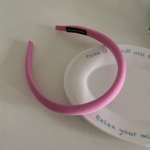 Dettaglio del cerchietto rosa imbottito con etichetta fatta a mano su piatto bianco